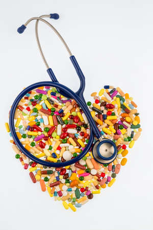 stethoscope and tablets in heart-shaped arrangement, symbol of heart disease, diagnosis and medicationの写真素材