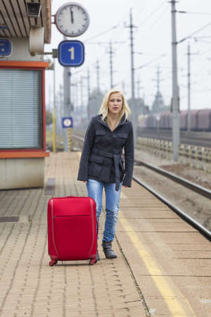 a young woman with suitcase waiting on the platform of a railway station on their train  train delaysの写真素材