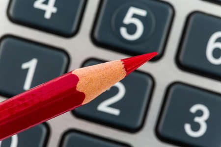 a red pen is on a calculator  save on costs, expenses and budget for bad economyの写真素材