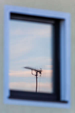 an antenna for a television set is reflected in the window of a houseの写真素材