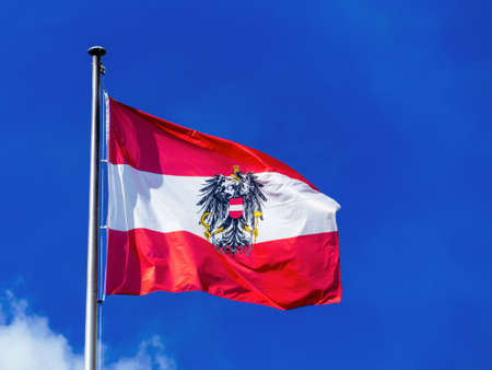 the austrian flag waving in the wind against a blue skyの写真素材