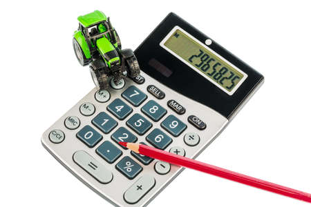 a tractor and a red pen is on a calculatorの写真素材