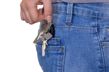 the hand of a young woman in jeans with keyring. keys for car and homeの写真素材