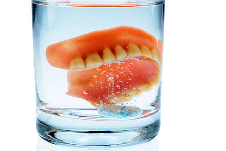 a denture is cleaned in a glass with water. proper hygiene.の写真素材