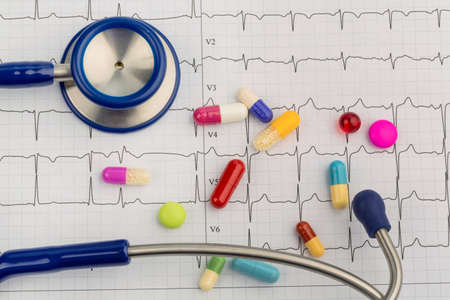 several tablets lie on an ekg. symbolic photo for diseases of the heart and circulationの写真素材