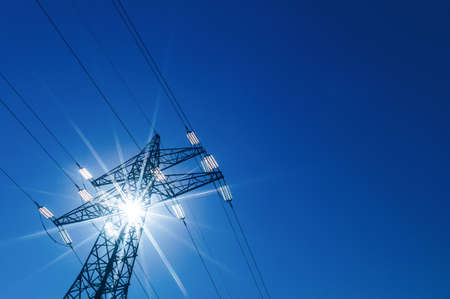 through a mast of a high voltage cable for electricity, the sun shines. solar energyの写真素材