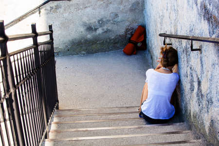 woman sitting on a staircase, symbol photo for loneliness, depression, sadnessの写真素材