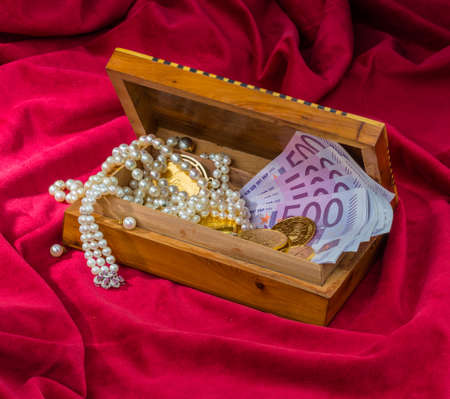 gold coins and bars with decorations on red velvet. symbolic photo for wealth, luxury, wealth tax.の写真素材