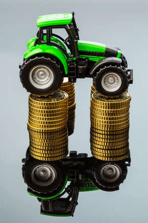 farmers in agriculture have to reckon with rising costs. higher prices for feed, fertilizer and plants. tractor with coinsの写真素材