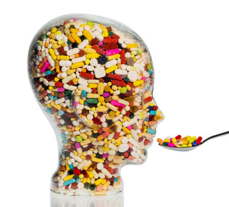 a head made of glass filled with many tablets. photo icon for drugs, abuse and addiction tablets.の写真素材