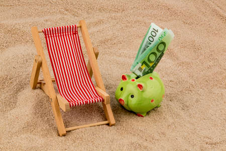 beach chair with euro currency on the sandy beach. symbolic photo for travel costs, vacation, holidayの写真素材