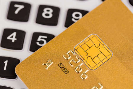 a gold credit card and a calculator. symbolic photo for cashless purchases and status symbols.の写真素材
