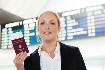 woman with passport and airline tickets at an airport waiting for her departure on holiday の写真素材