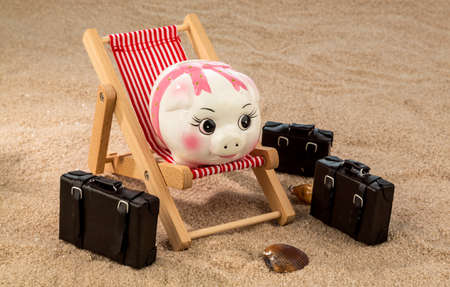 a piggy bank is located in a deck chair. symbolic photo for travel and low cost vacationの写真素材