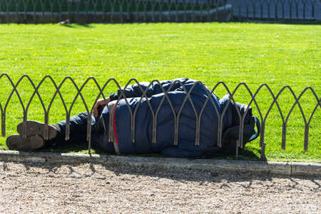 in homeless man lying in a park on a grass and sleeping