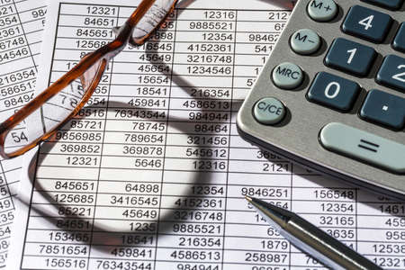 a calculator is on a balance sheet figures are statistics. photo icon for sales, profit and cost.