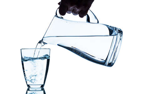 pure water is emptied into a glass of water from a pitcher. fresh drinking waterの写真素材