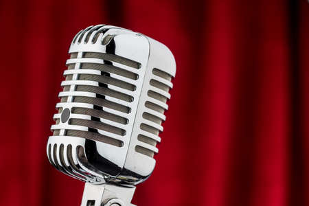 an old retro microphone against red velvet background.の写真素材