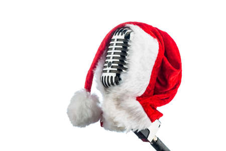an old retro microphone with santa hat against a red velvet background.の写真素材