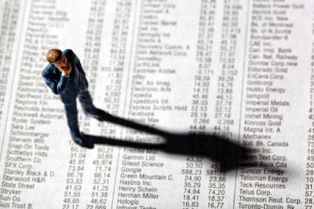 a small figure and the prices of shares in a newspaper. making money in the stock market. gains and losses in stock trading.の写真素材