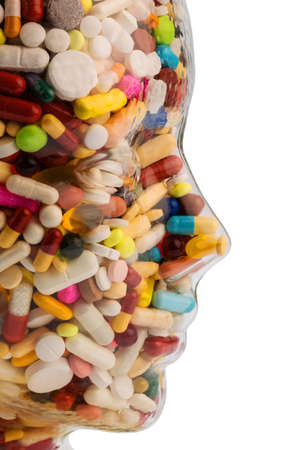 a head made of glass filled with many tablets. photo icon for drugs, abuse and addiction tablets.の写真素材