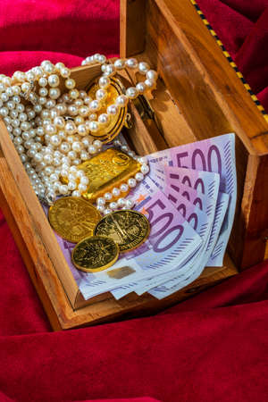 gold coins and bars with decorations on red velvet. symbol photo of wealth, luxury, wealth tax.の写真素材