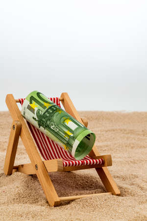 a deck chair with a euro banknote. symbol photo for saving on holiday and when travelingの写真素材
