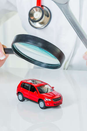 a model of a car is examined by a doctor. symbol photo workshop, service and car buying.の写真素材