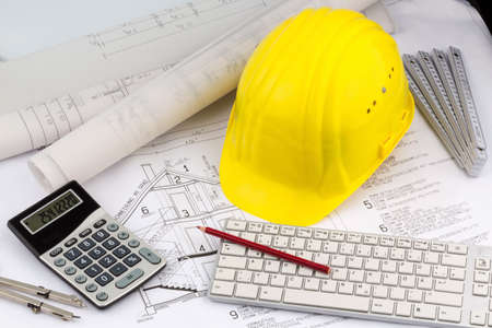 a blueprint of an architect with hard hat of a construction worker. symbol photo for financing and planning of a new home.の写真素材