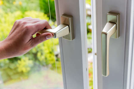 a woman opens a window to ventilate the apartment. fresh air in the roomの写真素材