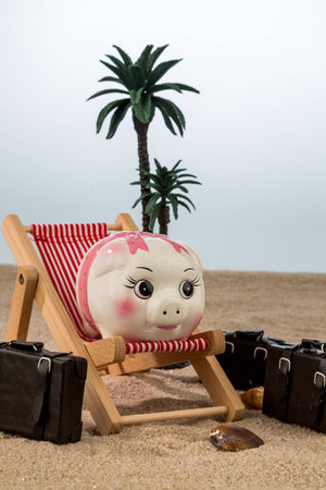 a piggy bank is in a deck chair. symbol photo for airline travel and expenses on vacationの写真素材