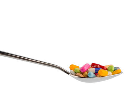 many colorful pills on a spoon. photo icon for tablets addiction and abuse of drugs.の写真素材