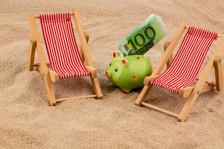 beach chair with euro currency on the sandy beach. symbolic photo for cost of travel, vacation, holidaysの写真素材