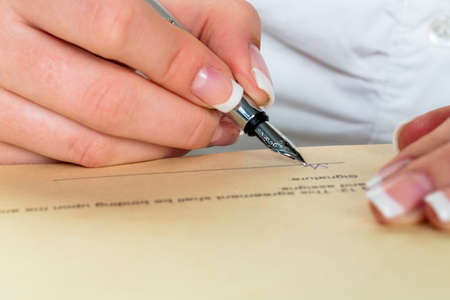 a woman signs a contract or a will with a fountain pen.