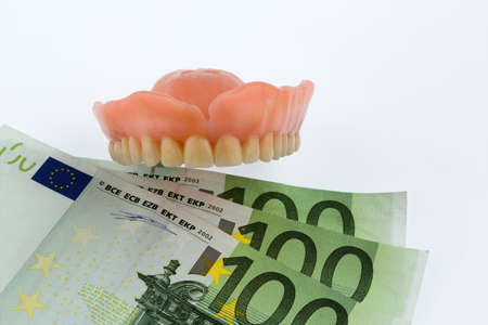 teeth and euro bills symbolic photo for dentures, treatment costs and paymentの写真素材