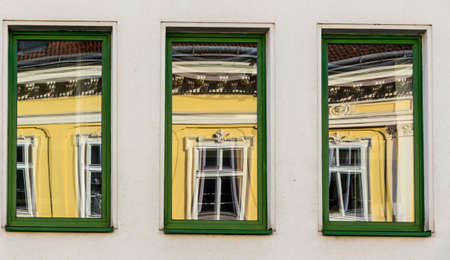 a renovated house reflected in modern windows of an office buildingの写真素材