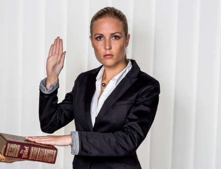 a woman says as a witness in court in a lawsuit. is sworn in and swears on the bible.の写真素材