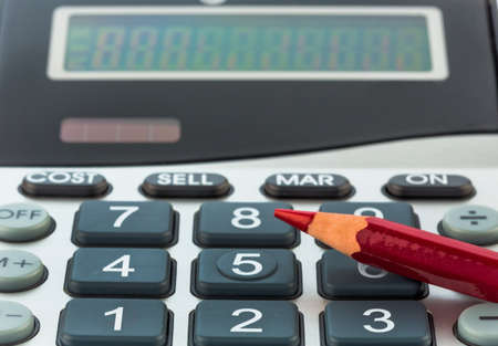 a red pen is on a calculator. save on costs, expenses and budget for bad economyの写真素材