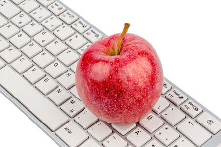 an apple is on the keyboard of a computer. symbolic photo for healthy and vitamin-packed snack.