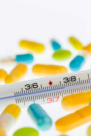 a clinical thermometer and tablets. symbolic photo for flu and colds