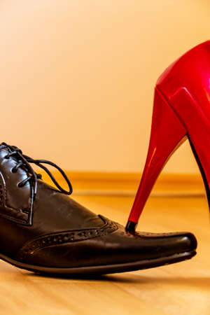 a woman takes a man with her high heels. symbolic photo for equality and bullying.の写真素材