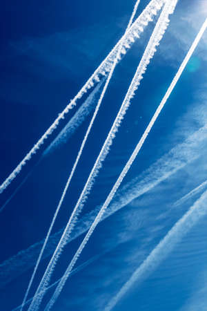 the contrails of multiple aircraft in front of blue skyの写真素材