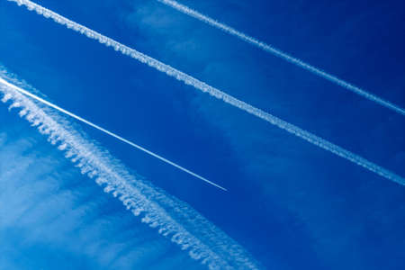 the contrails of multiple aircraft in front of blue skyの写真素材