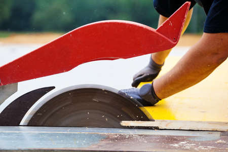 a construction worker cuts wood for shuttering on a construction siteの写真素材