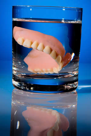 a denture is cleaned in a glass with water. proper hygiene.
