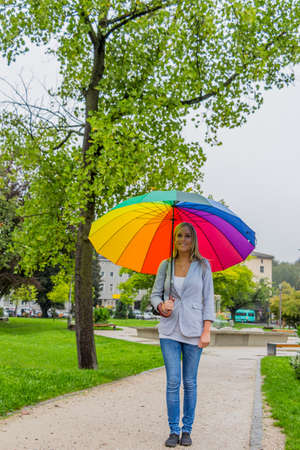 a young woman walks with a colorful umbrella in his hand walking in the rain.の写真素材