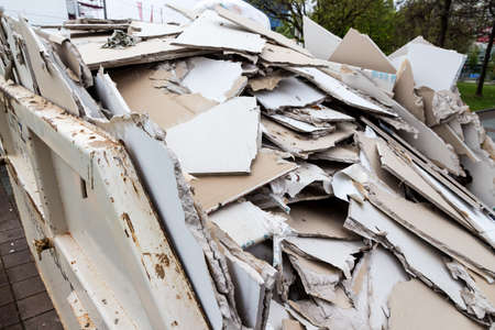 in a waste container stacks sheets of plasterboard for their disposalの写真素材