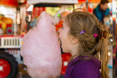 a little girl on a kirtag with cotton candy. fun and enjoying fairgroundの写真素材