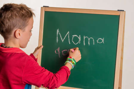 one child writes the word "mom" on a blackboardの写真素材