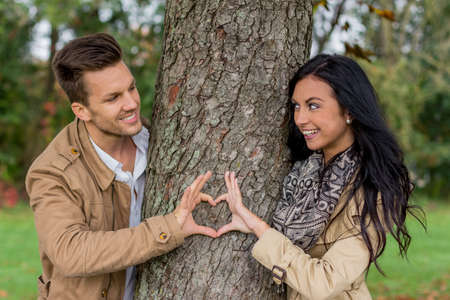 a young, laughed liebtes woman looking out from behind a treeの写真素材